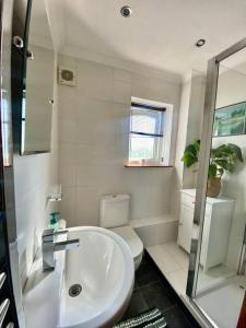 a white bathroom with a sink and a toilet at Apartment with parking, close to the Raigmore hospital in Inverness
