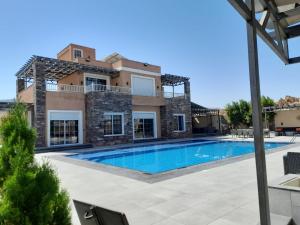 a villa with a swimming pool in front of a house at Taj Villa deadsea - Entire Villa with sea view in Sowayma