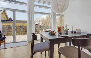Kelstrup StrandにあるNice Home In Haderslev With 3 Bedrooms And Wifiのダイニングルーム(テーブル、椅子付)、大きな窓が備わります。