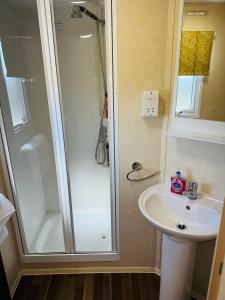 ein Bad mit einer Dusche und einem Waschbecken in der Unterkunft My Leisure Home On Fantasy Island in Ingoldmells