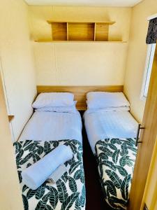 2 Betten in der Ecke eines kleinen Zimmers in der Unterkunft My Leisure Home On Fantasy Island in Ingoldmells