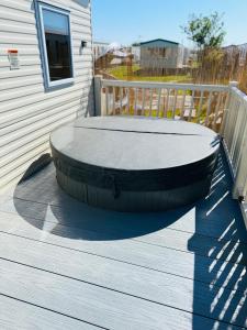 a fire pit sitting on a deck next to a house at My Leisure Home On Fantasy Island in Ingoldmells