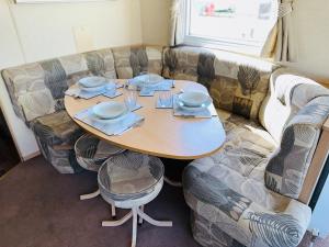 einen Tisch mit Tellern und Geschirr neben einer Couch in der Unterkunft My Leisure Home On Fantasy Island in Ingoldmells