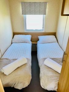 2 Betten in einem kleinen Zimmer mit Fenster in der Unterkunft My Leisure Home On Fantasy Island in Ingoldmells
