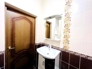 ein Badezimmer mit einem Waschbecken und einer Holztür in der Unterkunft Элитная квартира возле гипермаркета Дины in Aqtöbe