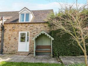 a stone house with a bench in front of it at Stonehaven in Kidderminster