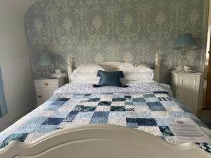 um quarto com uma cama com uma colcha azul e branca em Abbey Green Farm em Wem