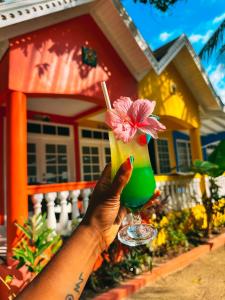 uma mão segurando uma bebida com uma flor dentro em THE BOARDWALK VILLAGE em Negril