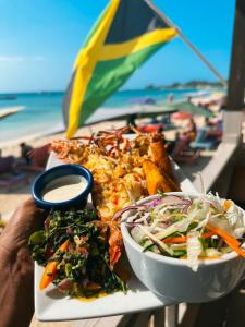 a plate of food on a table near the beach at THE BOARDWALK VILLAGE in Negril