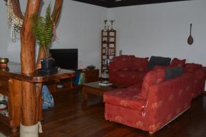 a living room with a red couch and a table at Villa MERAHI ... La villa d'Ange Fare Noa Mymy in Uturoa