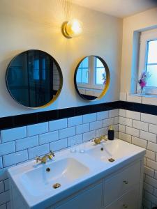 two mirrors above a white sink in a bathroom at Villa La Dune - Ontbijt & parking inclusief in Middelkerke