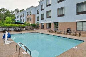 a pool with tables and chairs in front of a building at SpringHill Suites Pinehurst Southern Pines in Pinehurst