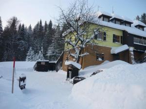ein schneebedecktes Haus mit einem Schneehaufen in der Unterkunft Penzion Ski in Karlova Studánka