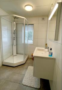 a white bathroom with a shower and a sink at Apartments Reine Lofoten in Reine