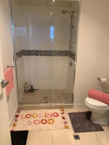 a bathroom with a shower and a toilet and a rug at Shared Homestay Tranquil Art Deco Private Room with Private Bathroom In Brunswick in Melbourne