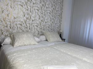 een bed met 2 kussens in een slaapkamer met behang bij Alojamiento Central Caravaca in Caravaca de la Cruz