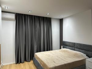 a bedroom with a bed and a large window at CozyStayApartments by Flow in Tirana