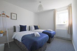 a bedroom with two beds with blue pillows and a window at StayRight 2Bed Apartment Overlooking Water with Free parking and 2 Bathrooms in Cardiff