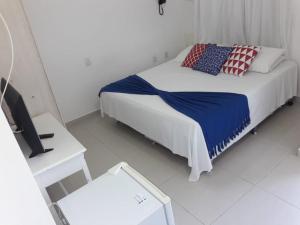 a white bedroom with a bed and a television at Hotel Maricá in Penha
