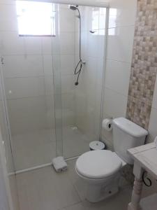 a white bathroom with a shower and a toilet at Hotel Maricá in Penha