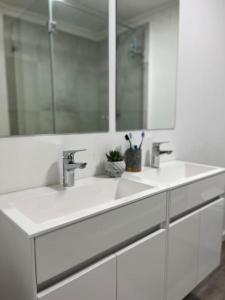 a white bathroom with two sinks and a mirror at Stunning Modern apartment Cape Town City Centre. in Cape Town