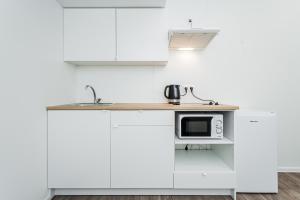 a kitchen with white cabinets and a counter with a microwave at Kalniečių st 126A Kaunas Students Home LT in Kaunas