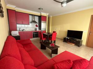 a living room with a red couch and a kitchen at Aguarii Cotillo in El Cotillo