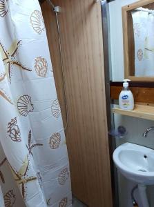 ein Bad mit einem Duschvorhang und einem Waschbecken in der Unterkunft Floating apartments in Rađenovići