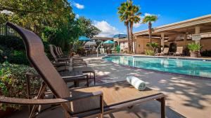 a resort pool with chairs and a bottle on a table at Best Western Plus Black Oak in Paso Robles