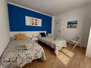 1 dormitorio con 2 camas y pared azul en Sleeping Sarria Hostel, en Sarria