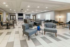 eine Lobby mit Stühlen und Tischen sowie ein Wartezimmer in der Unterkunft La Quinta Inn & Suites by Wyndham Ankeny IA - Des Moines IA in Ankeny