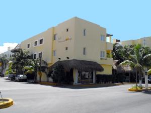 a large yellow building with palm trees in front of it at Hotel Riviera Caribe Maya in Playa del Carmen