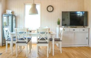 een eetkamer met een witte tafel en stoelen en een tv bij Kstenglck in Olpenitz