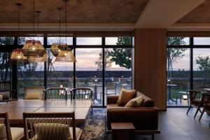 ein Wohnzimmer mit einem Tisch, Stühlen und Fenstern in der Unterkunft Fairfield by Marriott Kagoshima Sakurajima in Tarumizu