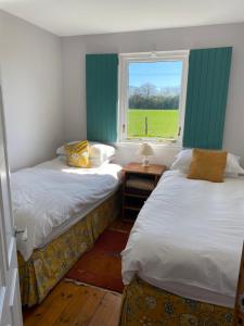 two beds in a room with a window at Gorton House and Cottages in Lasswade