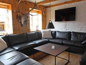 NeksøにあるHoliday home Nexø Xのリビングルーム(黒革のソファ、テーブル付)
