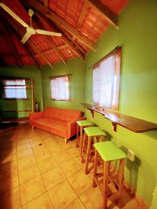 Aqua Lounge Bar & Hostal في بوكاس تاون: غرفة معيشة مع أريكة برتقالية وكراسي