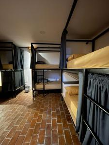 een kamer met 2 stapelbedden en een bakstenen vloer bij Ñañas Hostel in Cuenca