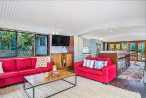 salon z 2 czerwonymi kanapami i stołem w obiekcie Fuller Holidays - Belongil Beachfront Pavilion, 18 Childe St w mieście Byron Bay