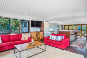 a living room with two red couches and a table at Fuller Holidays - Belongil Beachfront Pavilion, 18 Childe St in Byron Bay