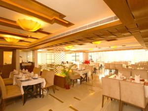 a dining room with tables and chairs in a restaurant at SP Grand Days in Trivandrum