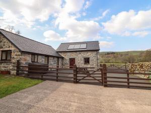 a stone house with a wooden fence in front of it at Beudy Bach Barn in Llanuwchllyn