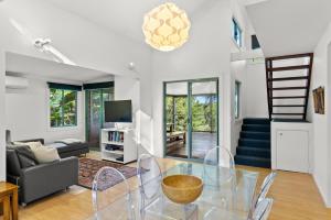 a living room with a glass table and a staircase at Fuller Holidays - Leah's Retreat - Relax in nature in Bangalow