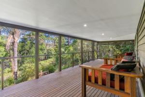 a screened in porch with a bench on a deck at Fuller Holidays - Leah's Retreat - Relax in nature in Bangalow