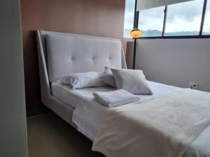 uma grande cama branca com duas almofadas em Apto Botero 1308 - WAIWA HOST em Floridablanca