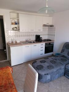 a kitchen with white cabinets and a sink and a couch at Apartments with parking space Dajla, Novigrad - 6935 in Novigrad Istria