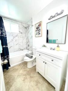 La salle de bains blanche est pourvue d'un lavabo, d'une baignoire et de toilettes. dans l'établissement Cozy house near Disney, Knott’s & Beach!!, à Fullerton