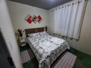 a small bedroom with a bed and a window at Morada Jaguary in Camanducaia