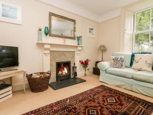 a living room with a fireplace and a couch at Banneth in Mawgan in Meneage