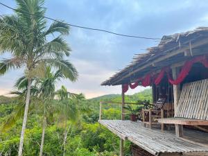 a house with a deck and a palm tree at Thornton's Sea View Cafe & Guesthouse in Siquijor